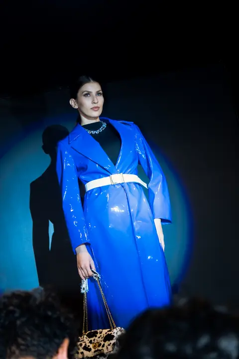 Modelo con gabardina azul de vinil bajo un foco
