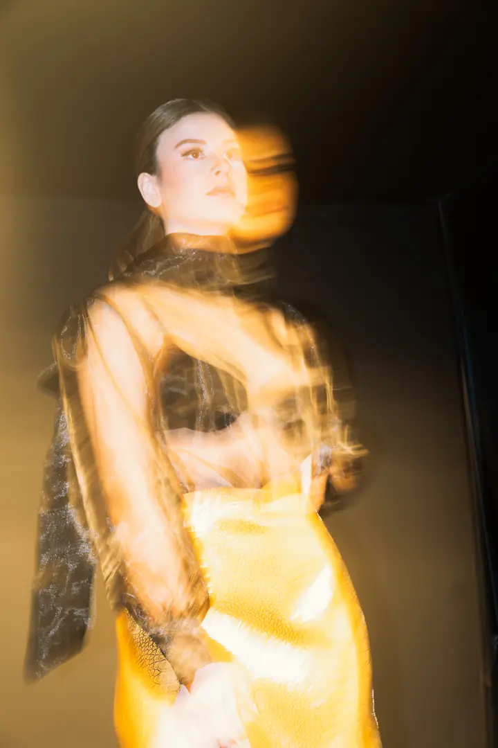 Modelo con vestido dorado en movimiento sobre la pasarela