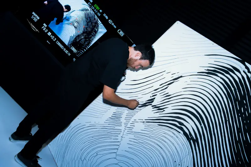 Artista pintando en vivo una obra en blanco y negro durante PasarelArt