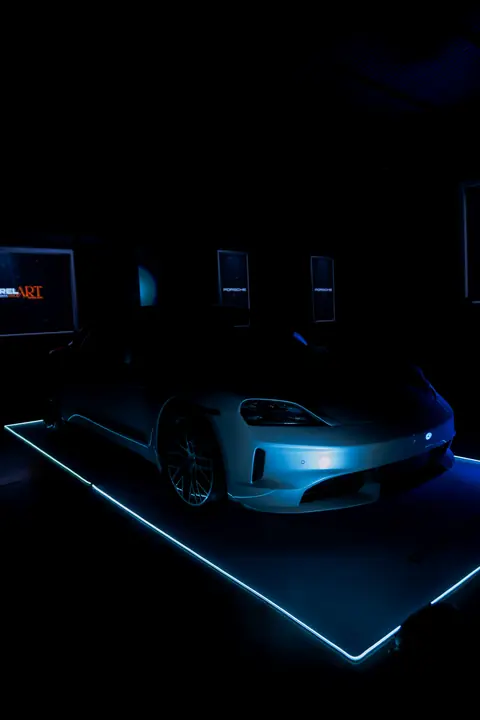 Porsche Taycan sobre plataforma iluminada en la sala oscura